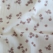 Cotton muslin with brown flowers on a vanilla background