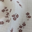 Cotton muslin with brown flowers on a vanilla background