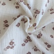 Cotton muslin with brown flowers on a vanilla background