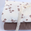 Cotton muslin with brown flowers on a vanilla background