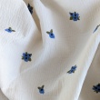 Cotton muslin with embroidered blue fruits on a natural background