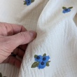 Cotton muslin with embroidered blue fruits on a natural background