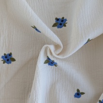 Cotton muslin with embroidered blue fruits on a natural background