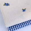 Cotton muslin with embroidered blue fruits on a natural background